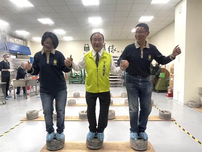 桃园市龙潭区「随缘茶空间」获得农产品初级加工场场证，农粮署长胡忠一（中）参访也体验脚踩制作仙草茶饼。（吕筱蝉摄）