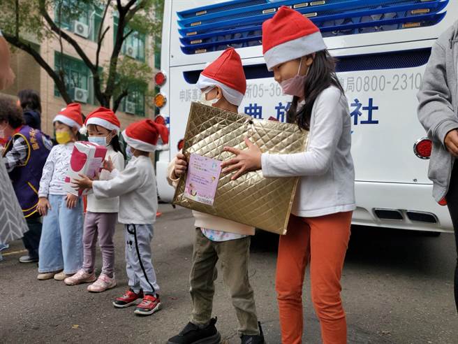 环球科大幼儿园小朋友帮忙传递礼物到车上。（周丽兰摄）