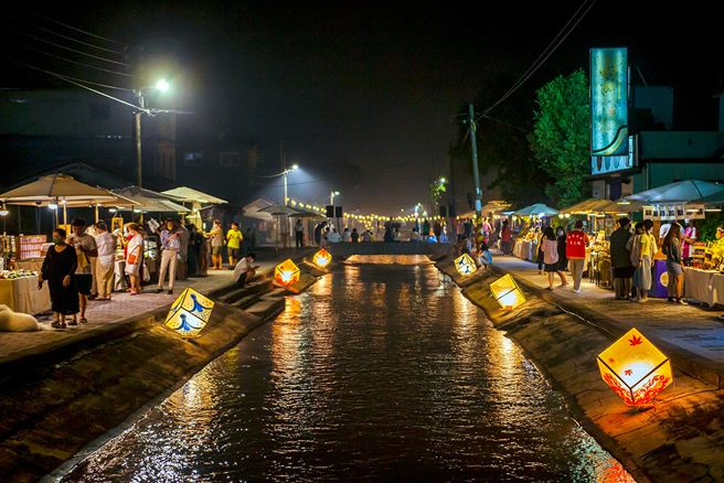 2022年中秋举办的「美浓水圳漫旅艺术节」和纸灯饰沿着水圳点亮夜晚，两旁匯集120家的秧光市集，吸引大批游客夜游美浓。(图片提供/米浓聚落)
