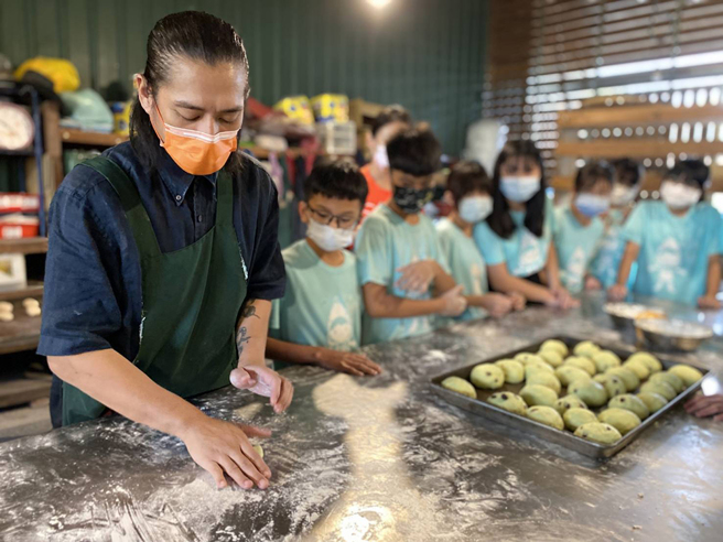 年轻的部落烘焙师Balee示范窑烤吐司的制作过程，与甲仙国小、小林国小的学童分享运用在地食材实践永续的概念。(摄影/Cindy Lee)
