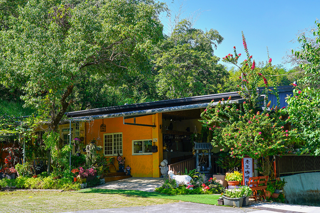 老三咖啡农场的亮黄色主屋依偎着大树，入口花木扶疏，妆点可爱的小天使和小矮人塑像，瀰漫悠閒的南欧乡村风情。(摄影/Cindy Lee)