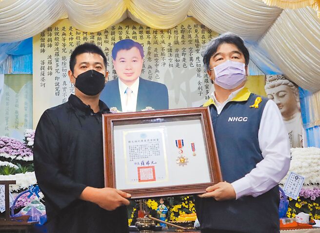 卫福部政务次长王必胜（右）15日出席热心药师赵伟正公祭，在灵前颁发「卫生福利专业奖章」，由赵的长子赵坤贤（左）代表接受。（吕妍庭摄）