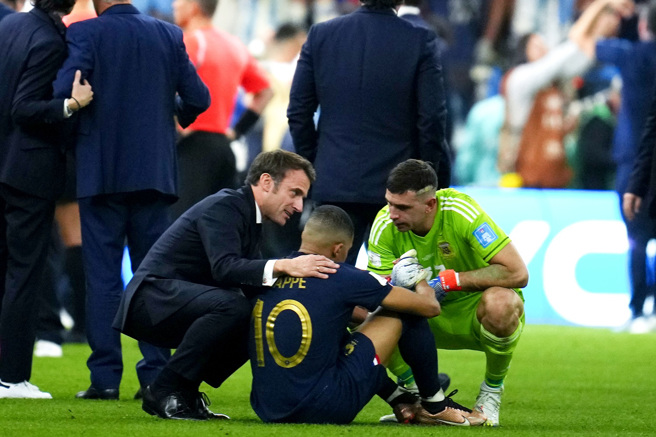 法国队18日在卡达世界杯冠军战中败给阿根廷，法国总统马克宏（Emmanuel Macron）走下球场安慰法国前锋姆巴佩（Kylian Mbappe），阿根廷23号门将马蒂内兹（Damian Martinez，着绿衣者）也上前安慰。（图／美联社）
