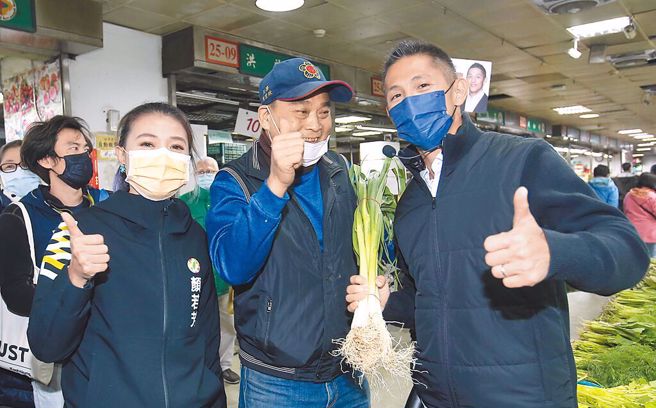 民进党台北市立委补选候选人吴怡农（右），18日与同党北市议员当选人顏若芳（左）一同前往滨江市场扫街，现场菜贩（中）送上蒜苗预祝「冻蒜」。（中时资料照，陈君玮摄）