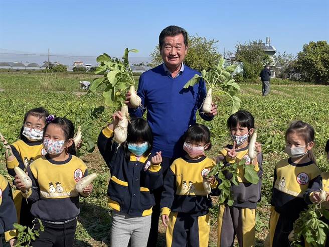 草屯镇长简景贤与幼儿园小朋友一起拔萝卜，为下月14日登场的活动宣传。（杨静茹摄）