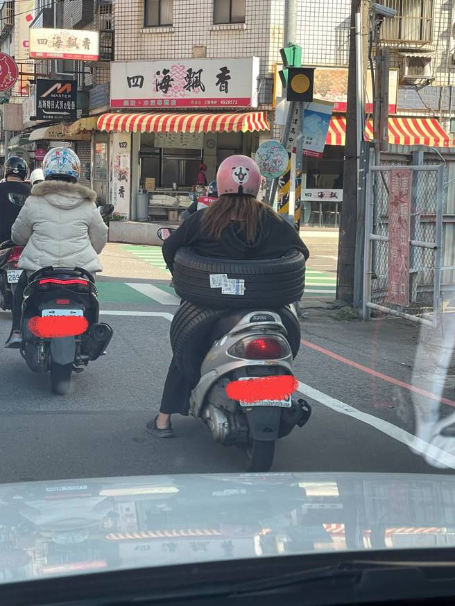 网友在路上发现一名女骑士骑机车「载2颗轮胎」，一颗轮胎套在坐垫，一颗则是套在身上，加上衣服也是全身黑，网友笑说「四轮传动，黑色米奇林现身」。（翻摄自脸书「路上观察学院」）