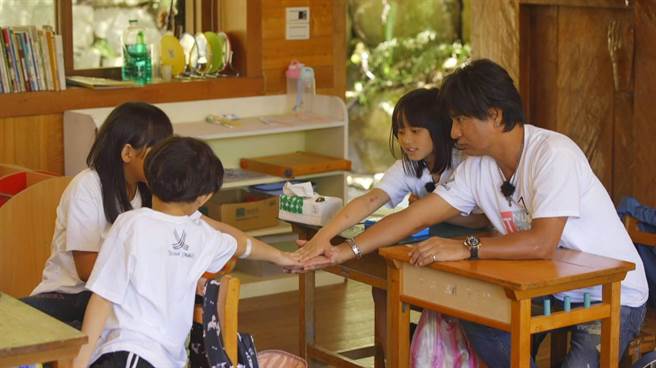 尤秋兴（右）和小学生相处融洽。（三立提供）