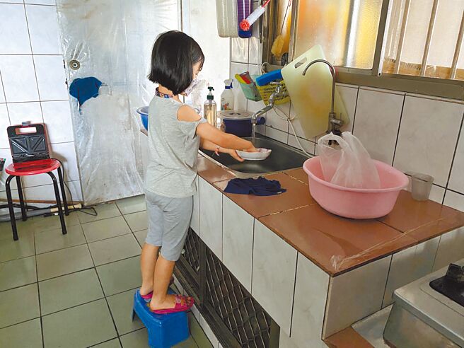 7岁的泡泡每天练习做家事，身高不够的她必须踩在椅凳上，才能符合流理台的高度。（中信慈善基金会提供）