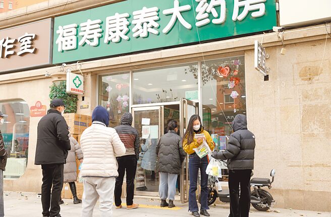 大陸多地掀起疫情海嘯，許多公務員病倒無法上班，導致公家機關相繼暫停業務辦理。圖為北京市民排隊購買居家治療常用藥。（中新社）