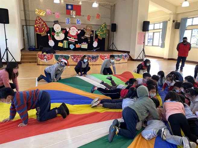 幼儿与家长一同将气球伞围成圈，变成圣诞甜甜圈。（金山国小提供）