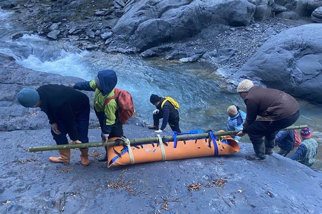 在霞喀罗古道坠谷失踪28天的郭男被寻获，搜救人员包裹遗体，从溪谷抬到路面。（新竹县消防局提供／罗浚滨新竹传真）