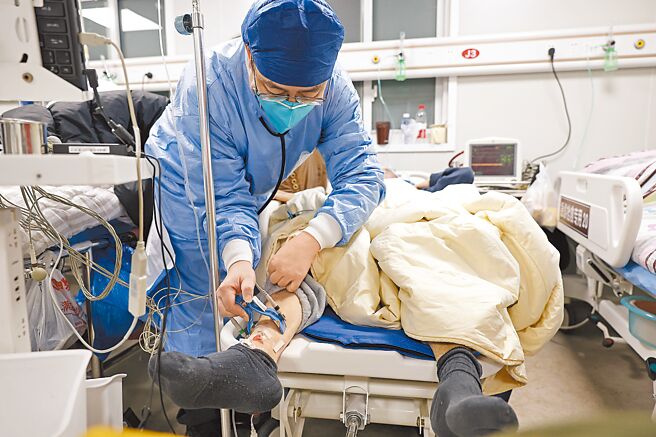 大陸將於2023年1月8日調整新型冠狀病毒感染為乙類乙管。圖為上海市同濟醫院醫護人員為患者進行檢查。（中新社）