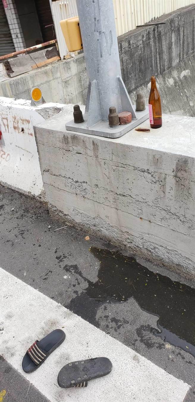現場在護欄上發現1支米酒瓶、拖鞋，疑似是老翁酒後摔落大排。（讀者提供／張毓翎台南傳真）