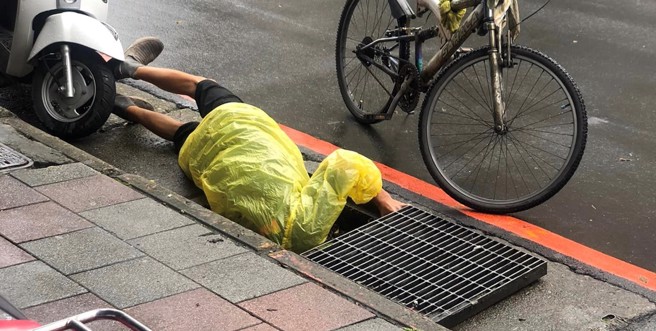 一名阿伯在寒冬中把整颗头探进去水沟盖，让人好奇究竟是为了什么。（图／翻摄自爆废公社）

