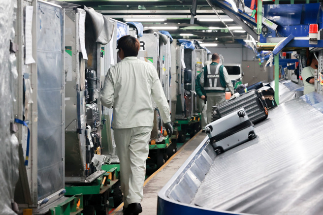 长荣航勤不满年终仅领1个月，元旦连假集体请假不出勤表达抗议，1日逾40航班、超过3000名旅客出境受到影响。图为少数上班的长荣航勤人员在地下室行李转盘搬运旅客行李。（陈麒全摄）