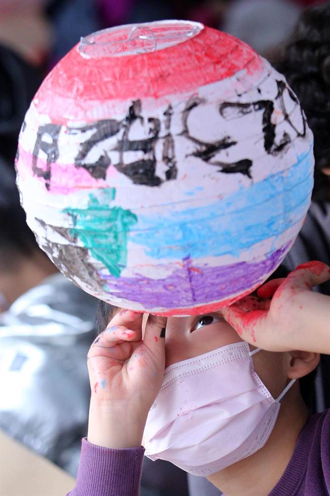 新北市新庄区公所迎新年庆元宵系列活动，首波主打的「彩绘灯笼·幸福兔U」活动2日热闹登场，小朋友创作完成属于自己的兔年提灯后，俏皮地举起提灯细细端详一番。（黄世麒摄）