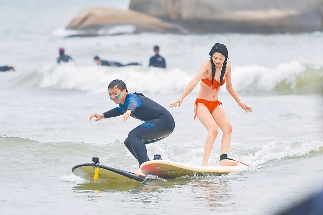 大陸公衛專家發表研究指出，北京、上海、廣州、重慶等城市，已走過疫情高峰，感染接近尾聲。圖為元旦假期遊客到海南三亞衝浪。（中新社）