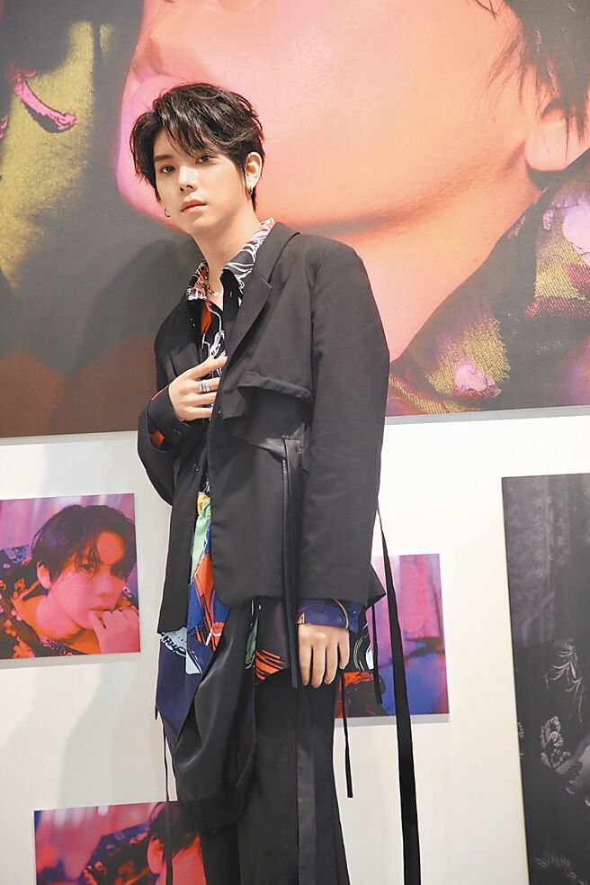 楊宇騰昨出席主題攝影展，與自己的攝影照片合影。（泓康天下提供）