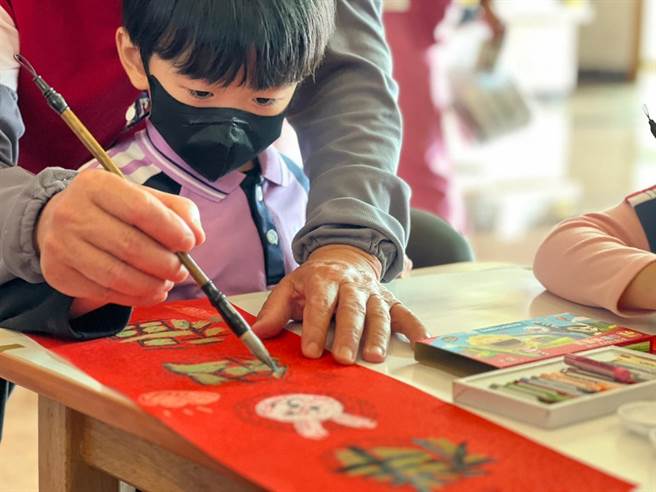 义大医院10日举办新春挥毫活动，图为长辈指导孩童写春联。（义大医院提供／林瑞益高雄传真）