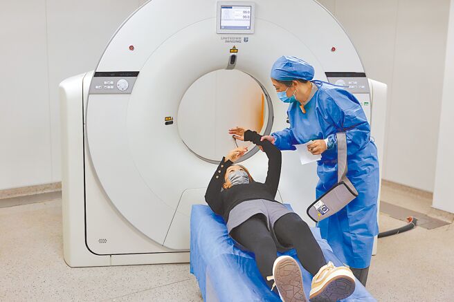 大陆各地体检机构、医院陆续推出「阳康」体检套餐或康復门诊，甚至有民营机构短短半个月销售额就逼近上亿元人民币。图为1月9日，上海市闵行区申鑫社区卫生服务中心医护人员在CT扫描室为市民进行拍片前准备。（中新社）