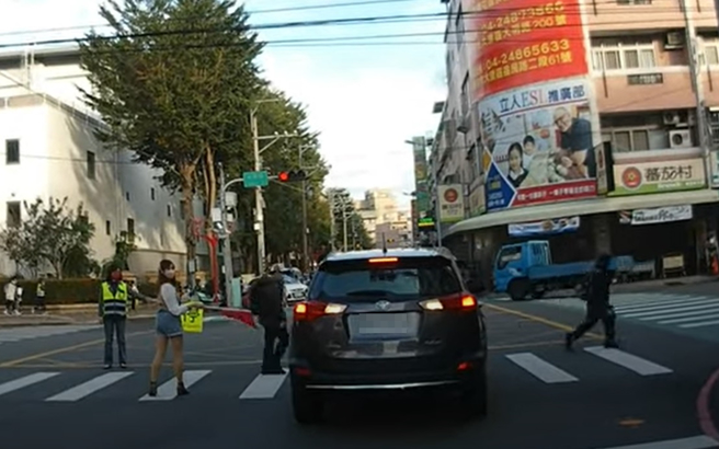 休旅車闖路紅燈失敗，車子壓在斑馬線上，但下一秒竟倒車後退，網友也笑翻「是我遇到這情況也會倒車回來再看一眼美腿老師」。（翻攝自YouTube頻道「WoWtchout - 地圖型行車影像分享平台」）