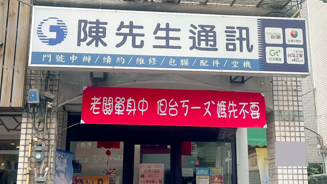 新竹一名網友發現一間通訊行門口高掛紅色布條，上面寫「老闆單身中，但『台ㄎㄧㄡˋ媽先不要』」。（圖／網友授權提供）