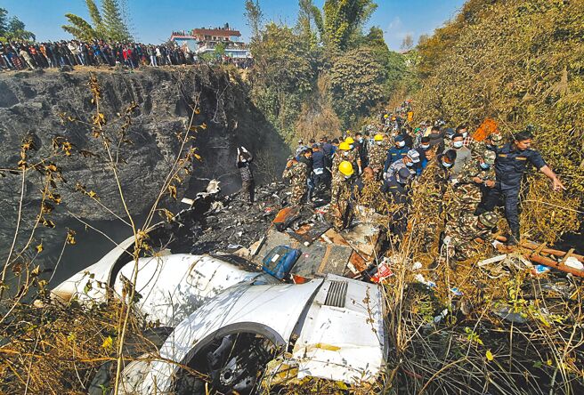 尼泊尔救援队在飞机坠毁现场进行救援。（路透）