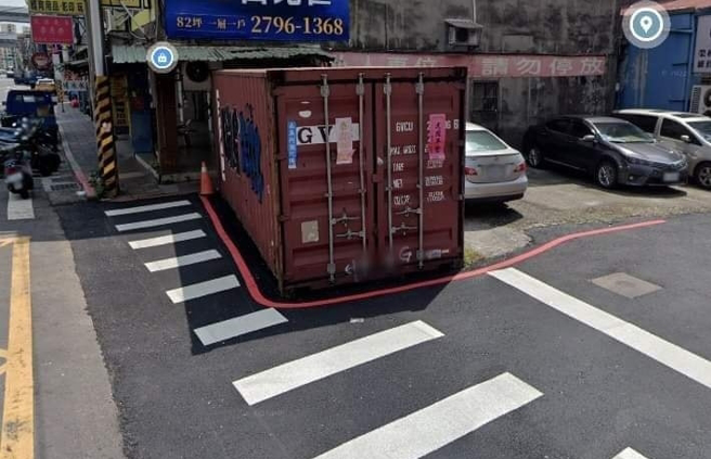 台北内湖一处道路的斑马线被发现一部分被大型货柜「压着」，斑马线因此变得长短不一，影响路人行走，连一旁的红线都沿着货柜周围划设。（翻摄自脸书「爆废公社」）