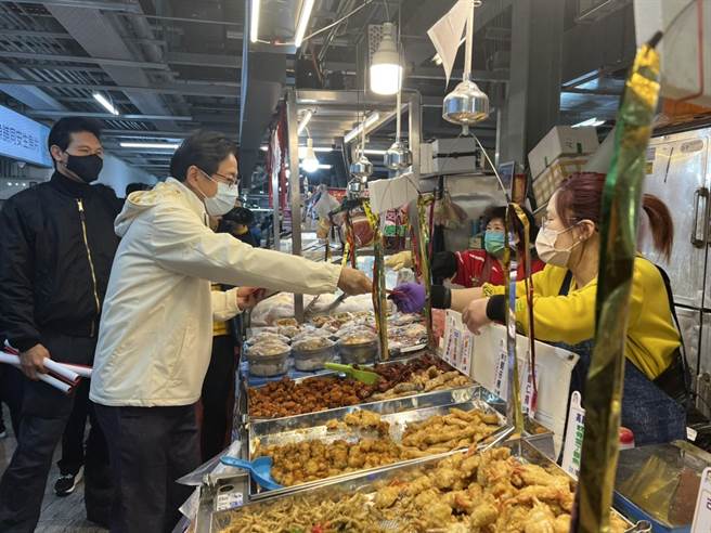 桃园市长张善政17日到新永和市场发福袋，民眾排队抢拿，他也逐一关心摊商。(蔡依珍摄)