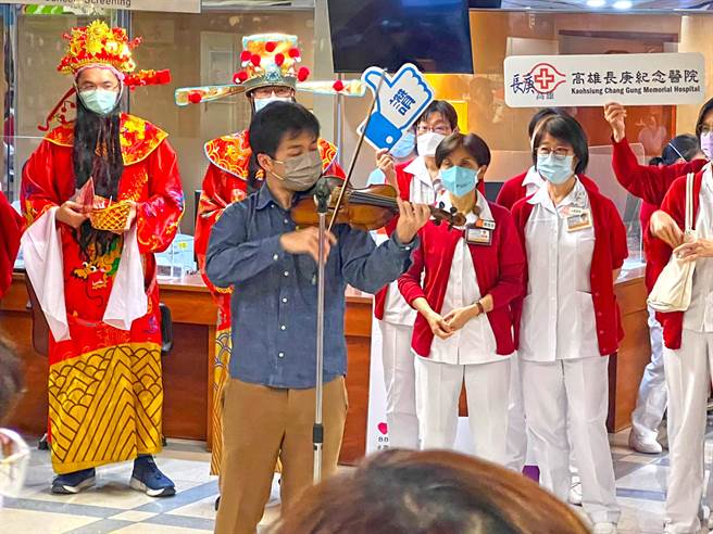 農曆年即將到來，小提琴家魏靖儀17日受邀到高雄長庚醫院「快閃」演出賀年，醫師和行政主管也扮演財神爺，與護理師們在一樓藥局前發送紅包袋和棒棒糖給病人和民眾。（高雄長庚醫院提供／袁庭堯高雄傳真）