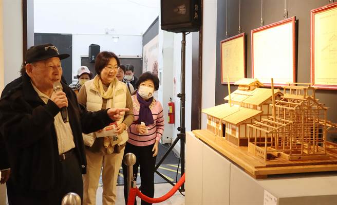高龄80岁的桧木建筑模型艺师陈振龙与学生在嘉义县表演艺术中心办师生联展，现场展出20件作品，作工细致又小巧，昨开幕会后，陈振龙 （左一）一一讲解作品。（吕妍庭摄）