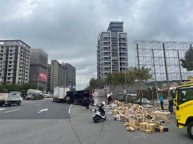 新北市五股区今(17)日中午发生一起货车翻覆意外，有辆联结车疑似迴转时重心不稳，结果后方第2节的货柜在路口翻覆，现场货物散落一地。(黄敬文翻摄)