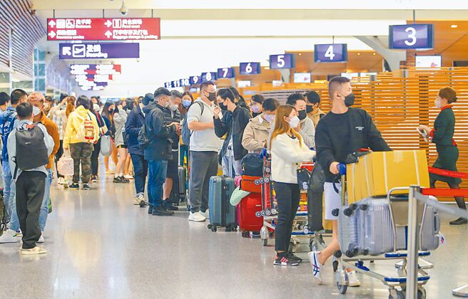桃园国际机场预估2023年春节疏运期间（1月19日至1月30日），出入境旅客的高峰将落在收假前两日的1月28日，约为9万4000人次。图为桃园机场出境旅客大排长龙办理出境报到手续。（陈麒全摄）