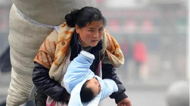 13年前感动全网的「春运母亲」彝族妇女巴木玉布木，背着比人还高的巨大行囊，一手抱着襁褓中熟睡的孩子，踏上春运返乡路。（新华社）