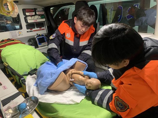 竹东消防分队队员林冠廷、郑育承小年夜协助孕妇在救护车上急产，两人模拟当时接生状况。（新竹县消防局提供）
