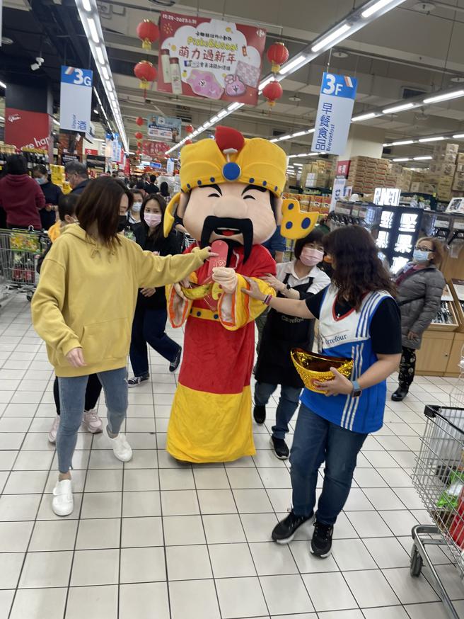 家乐福新店店涌入人潮抢购福袋，现场邀请财神爷发送红包袋。（家乐福提供）