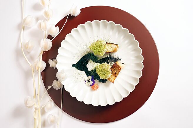 日胜生加贺屋〈天翔厅〉的〈颚无鱼炭火烧〉，主体是烤鯃仔鱼，主厨将乌贼墨汁、蛋黄酱、越光米制成的浓稠黑酱做盘饰模拟松枝，使用抹茶粉模拟松叶。图／日胜生加贺屋