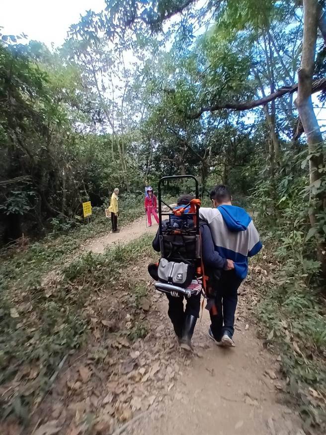独攀笠顶山体力不支，警消以搀扶方式协助男子下山。(屏县消防局提供)