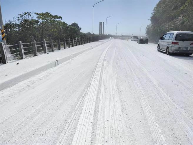 新北市贡寮区滨海公路拖板车载运的石灰散落路面，现场犹如雪国。（新北市警察局提供／张志康新北传真）