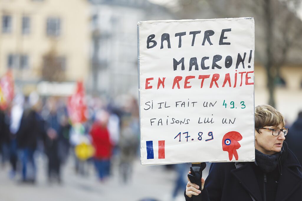法國民眾不滿年金改革走上街頭，抗議者舉牌對總統馬克宏喊話，若執意年改，將重演法國大革命。圖／美聯社