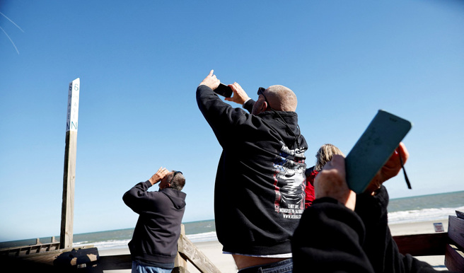 美國南卡羅來納州民眾4日在海邊用手機捕捉美軍F-22戰機擊落大陸偵察氣球的歷史性時刻。（圖／路透社）