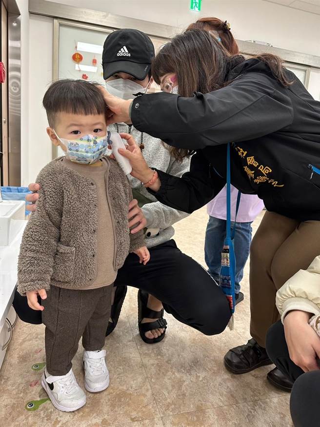 社会局长廖静芝上午协助托育人员为小朋友量体温。（台中市政府提供）