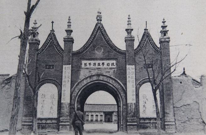 图为日军1938年的抗日学生游击队学校，一名日军观看学校大门上的宣传文字。上联：加强抗日军队中的政治工作；下联：肃清汉奸份子巩固抗日后方。右：敌进我退，敌驻我扰；左：敌疲我打，敌退我追翻拍图片（中新社）