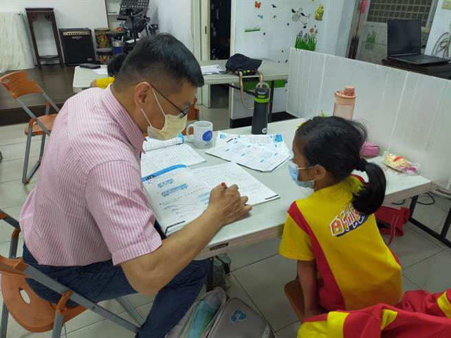 明穗教会何建荣牧师指导孩子课业。（新北市社会局提供）