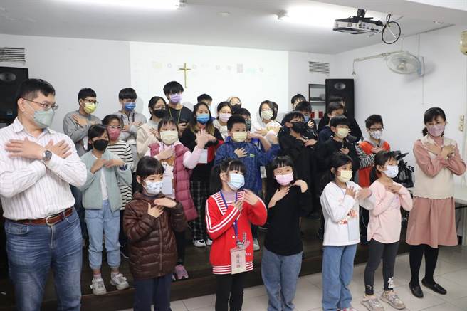 明穗教会何建荣（左1）和陈莹真（右1）牧师与孩子合唱。（新北市社会局提供）