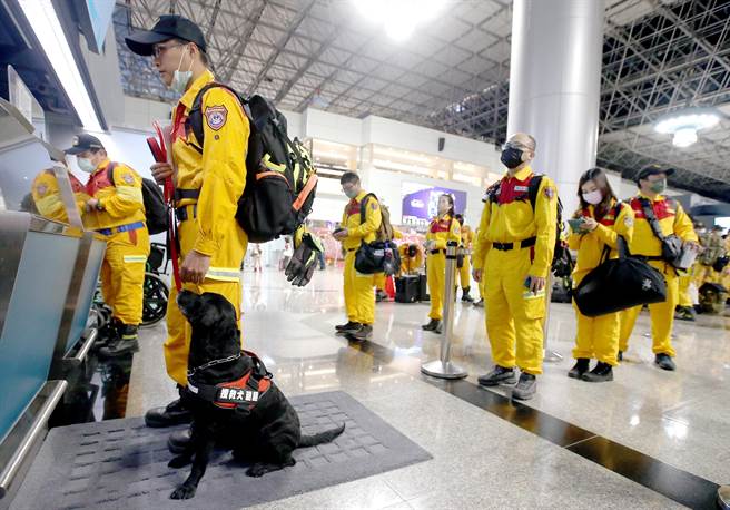 在桃園機場第二航廈內隊員牽著搜救犬辦理登機手續。（范揚光攝）
