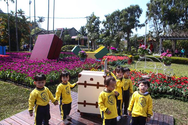 2023士林官邸郁金香展公园处配合今年遇见爱的主题，员工们也亲自打造一系列沉浸式展区，展区内的装置物如荷兰风车、木鞋、绘马、行李箱等，都是同仁手工制作。（邓博仁摄）