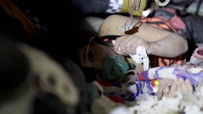 「白頭盔」 (White Helmets)官方照號發布一段畫面，一名女童躺在坍塌的建築物內等待救援，成員們跪地唱歌安撫情緒，感人舉動惹哭一票網友。(圖/路透社) 