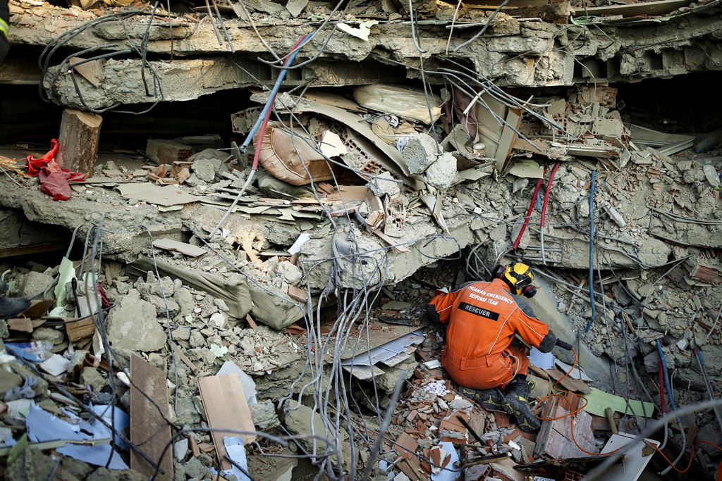 土耳其强震重灾区哈泰省（Hatay）一群救难人员在瓦砾堆中搜救时，上方砖瓦突然松动、狂泻，当场掩埋一名救难人员。图为救难人员在高耸的瓦砾堆下救灾。（图／美联社）(photo:ChinaTimes)