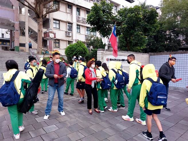 迎接开学日到来，淡水国中校长王洁雯及家长会长郭启沐在校门口发送小红包给学生。（淡水国中提供）
